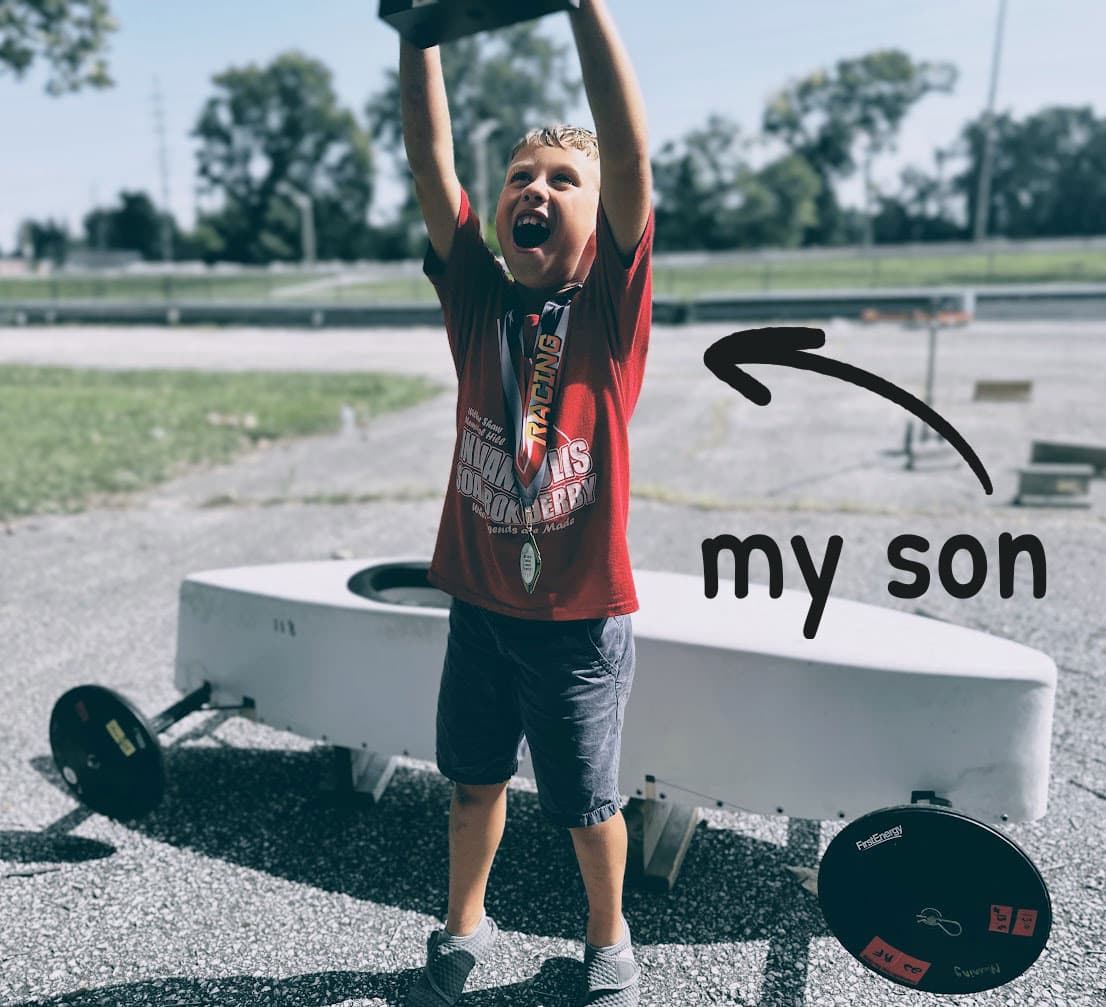 Hudson Manning holding trophy in front of soap box car