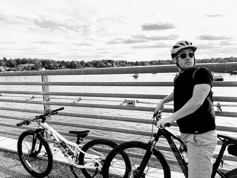 Schyler Manning on a mountain bike going across a bridge over water